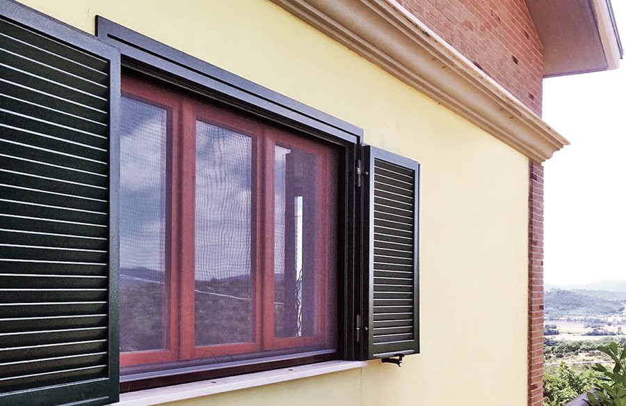 Finestra con persiane verdi su muro giallo.